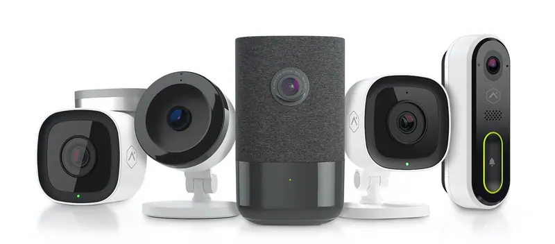 Lineup of Alarm.com indoor and outdoor cameras, a fabric covered indoor camera, and a video doorbell
