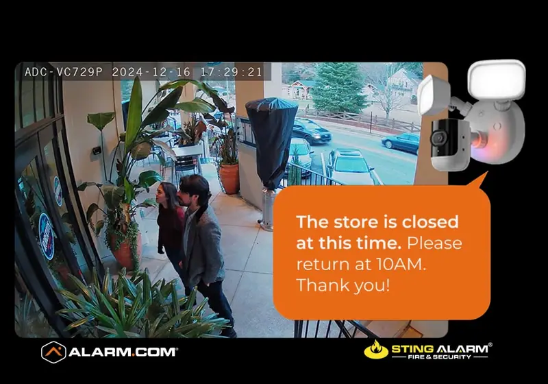 Camera view of a couple at a storefront with a voice message: The store is closed at this time. Please return at 10AM