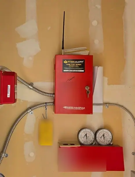 Sting Alarm StingNet AES-IntelliNet radio transmitter mounted beside a fire sprinkler riser and pressure gauges