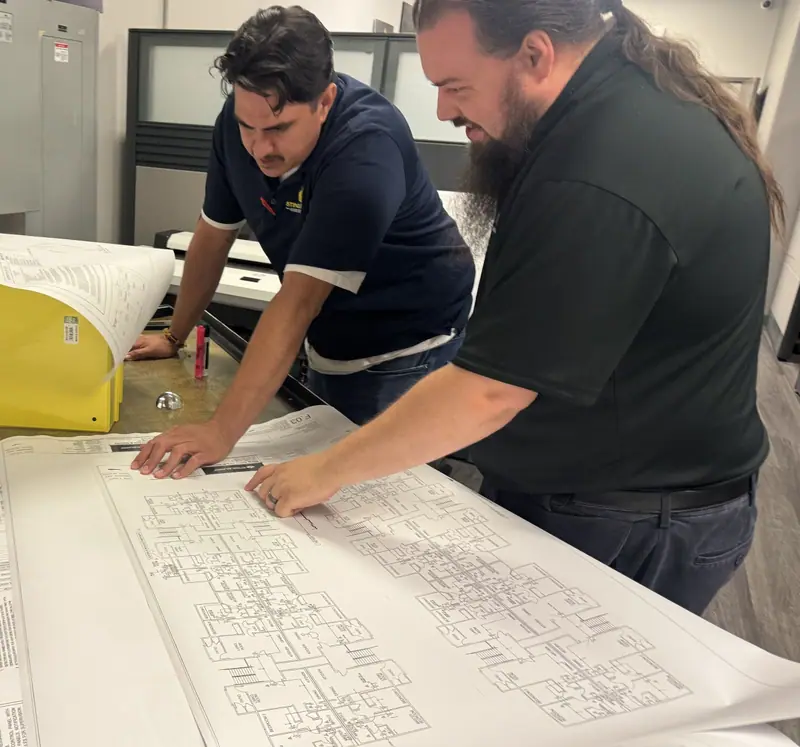 Two Sting Alarm team members reviewing building plans before a commercial fire and security installation